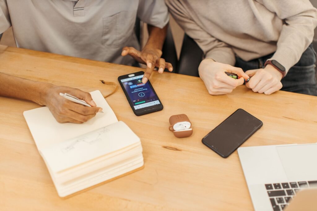Adult checking meeting details on a smartphone beside a notebook