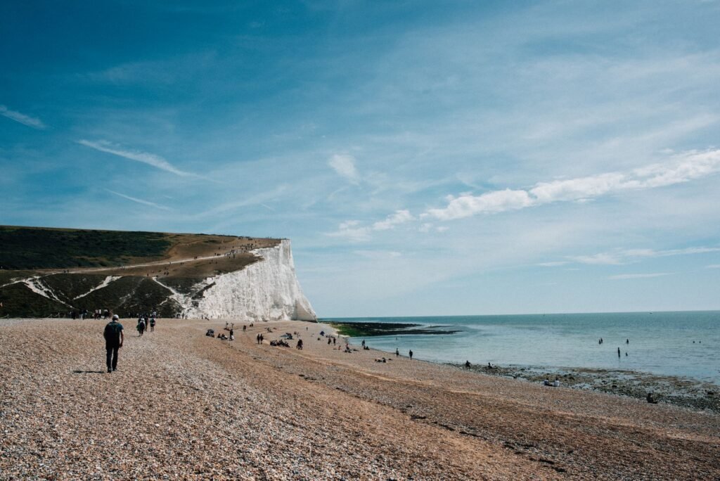 Breathtaking view of the Seven Sisters cliffs with a pebbled beach and clear blue sky in Eastbourne, England.