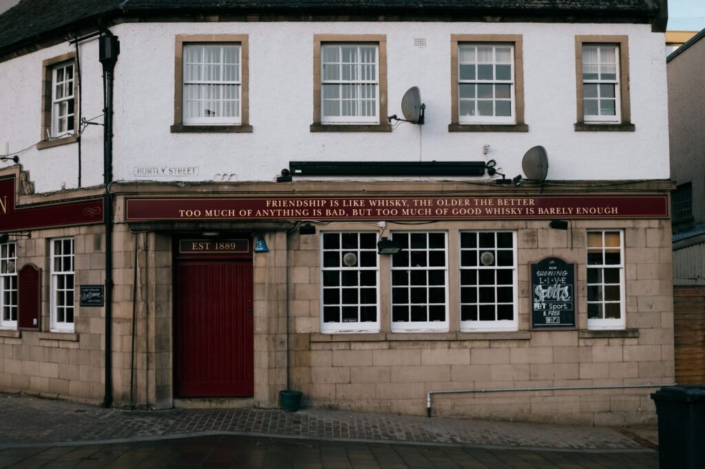 Exterior view of Glenalbyn Bar in Inverness, featuring a whisky-related quote.