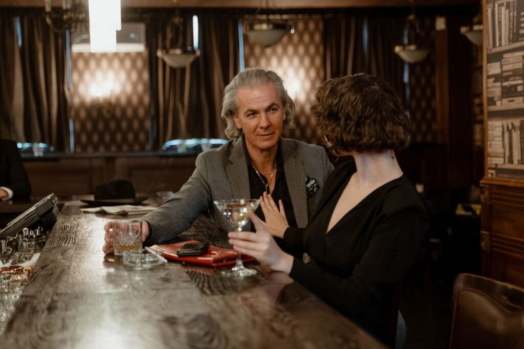 A sophisticated couple enjoying drinks and conversation in an intimate bar atmosphere.