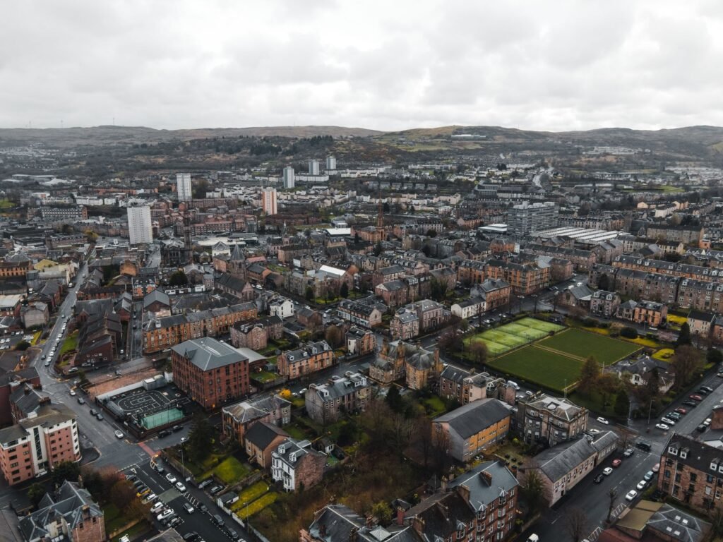 Aerial view of a picturesque town in Scotland, showcasing architecture and landscape amidst cloudy skies.