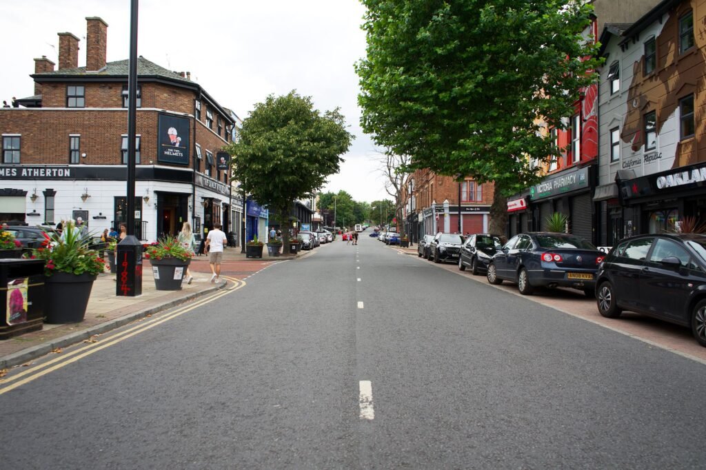 Lively street scene in Liverpool, England with shops, cars, and pedestrians.