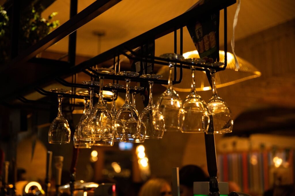 Warmly illuminated bar interior with hanging wine glasses and cozy atmosphere. Ideal for nightlife and hospitality themes.
