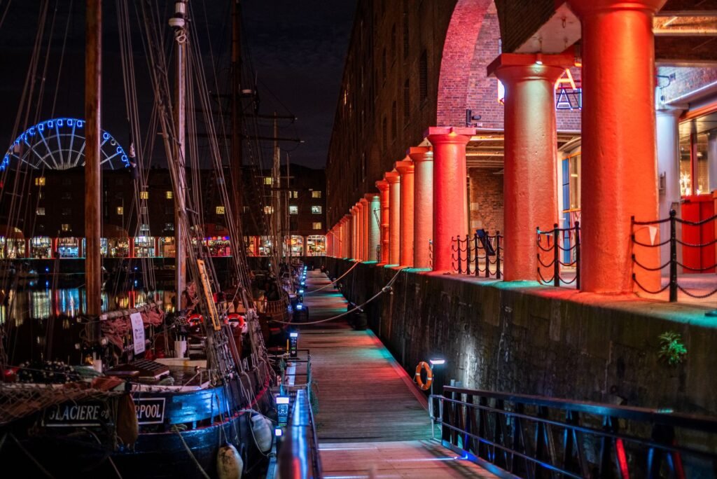 Atmospheric night scene of Liverpool's Royal Albert Dock with vibrant lights and boats.