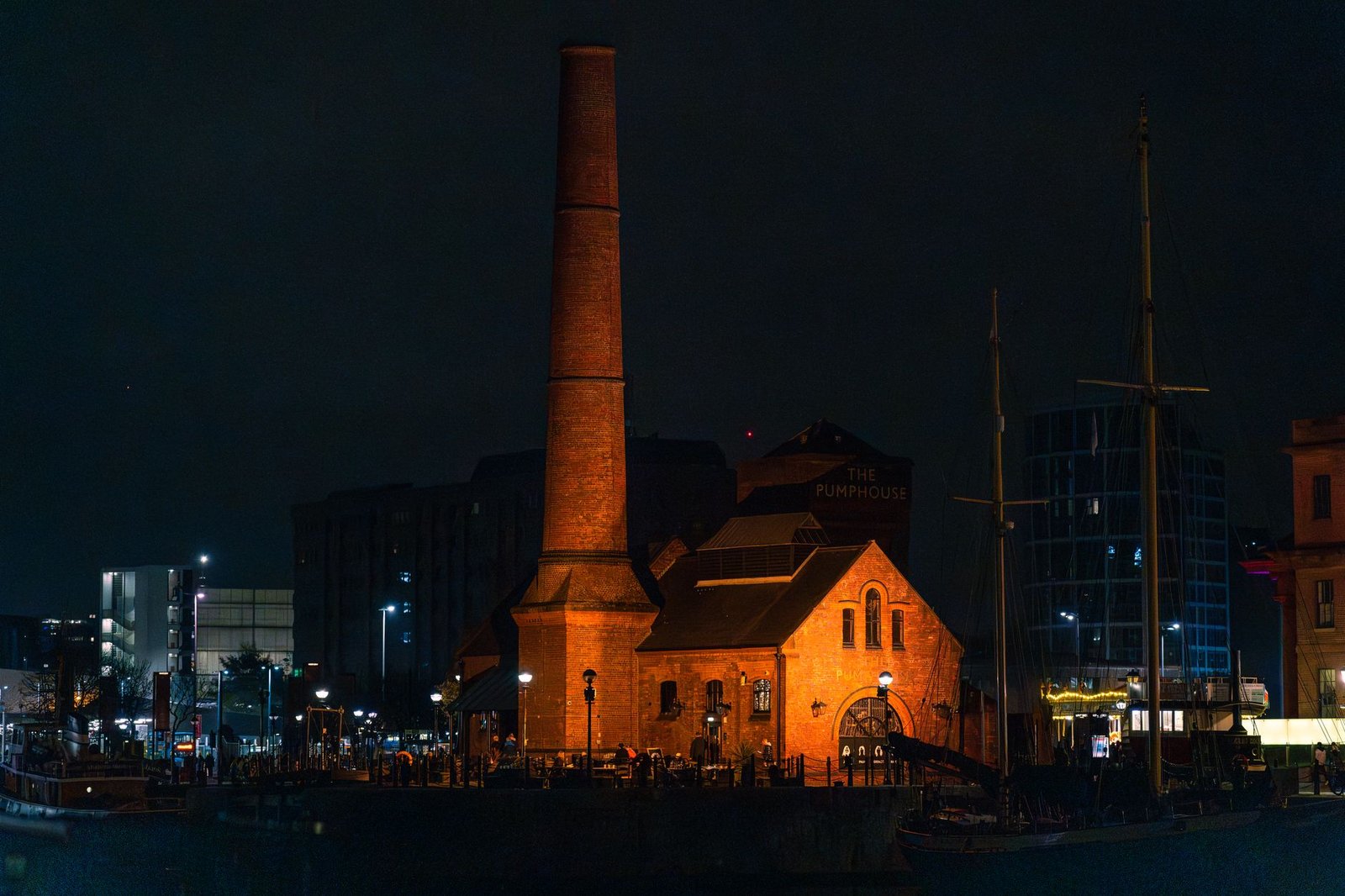 Night view of the iconic Pumphouse building with its tall chimney surrounded by city lights.