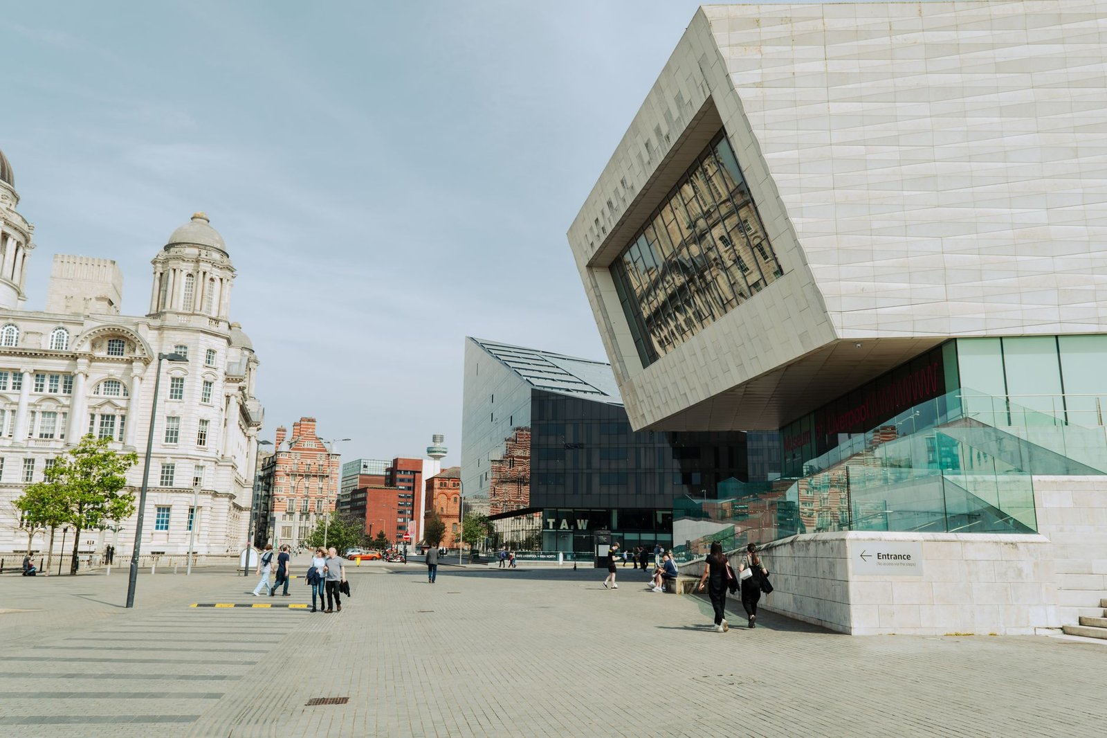 View of modern and historical architecture in Liverpool, England with pedestrians in a city square.