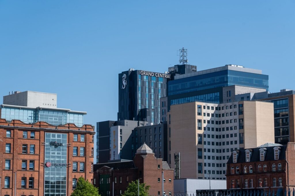 A daylight view of Belfast's urban skyline highlighting the Grand Central Hotel against a clear blue sky.