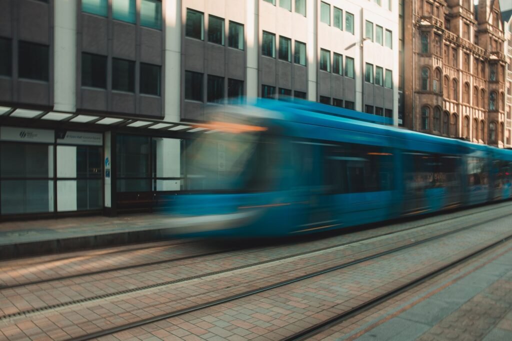 A blue tram speeds through Birmingham's cityscape, capturing urban movement and architecture.