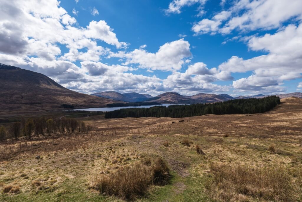 Beautiful landscape of Scottish Highlands with lake, hills, and expansive sky.