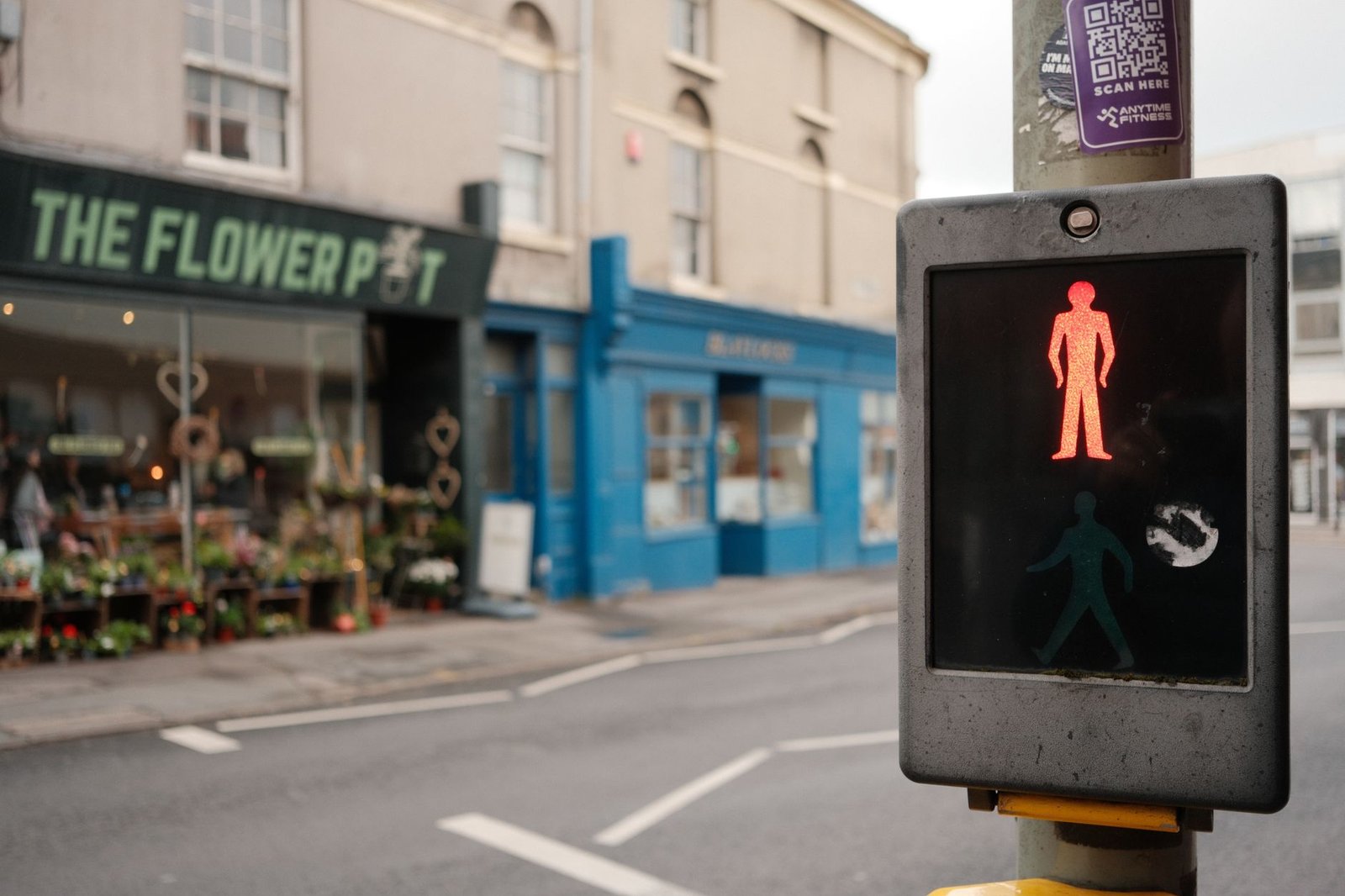 Street view of Swindon, UK featuring a red pedestrian traffic light with shops in the background.