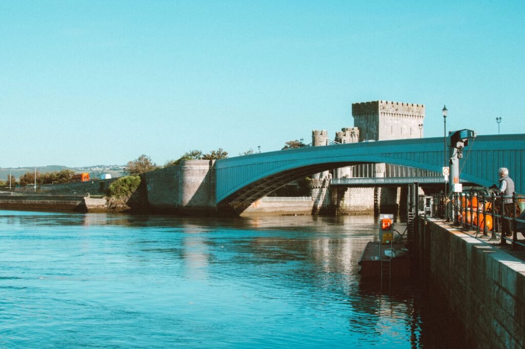 Peaceful scene of Conwy Castle and a modern bridge over the river in Wales.