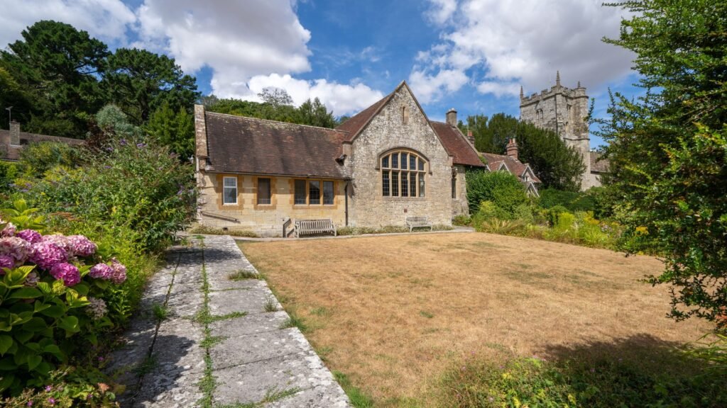 Charming historic building with garden in East Knoyle, England, under a bright summer sky.