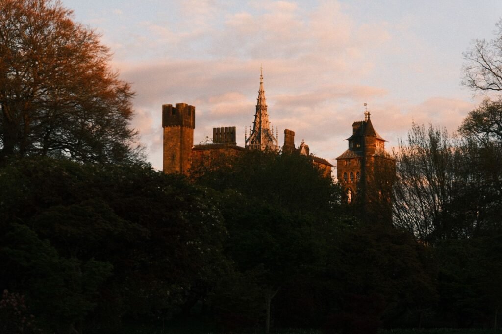 Scenic view of Cardiff Castle surrounded by lush spring trees during sunset.