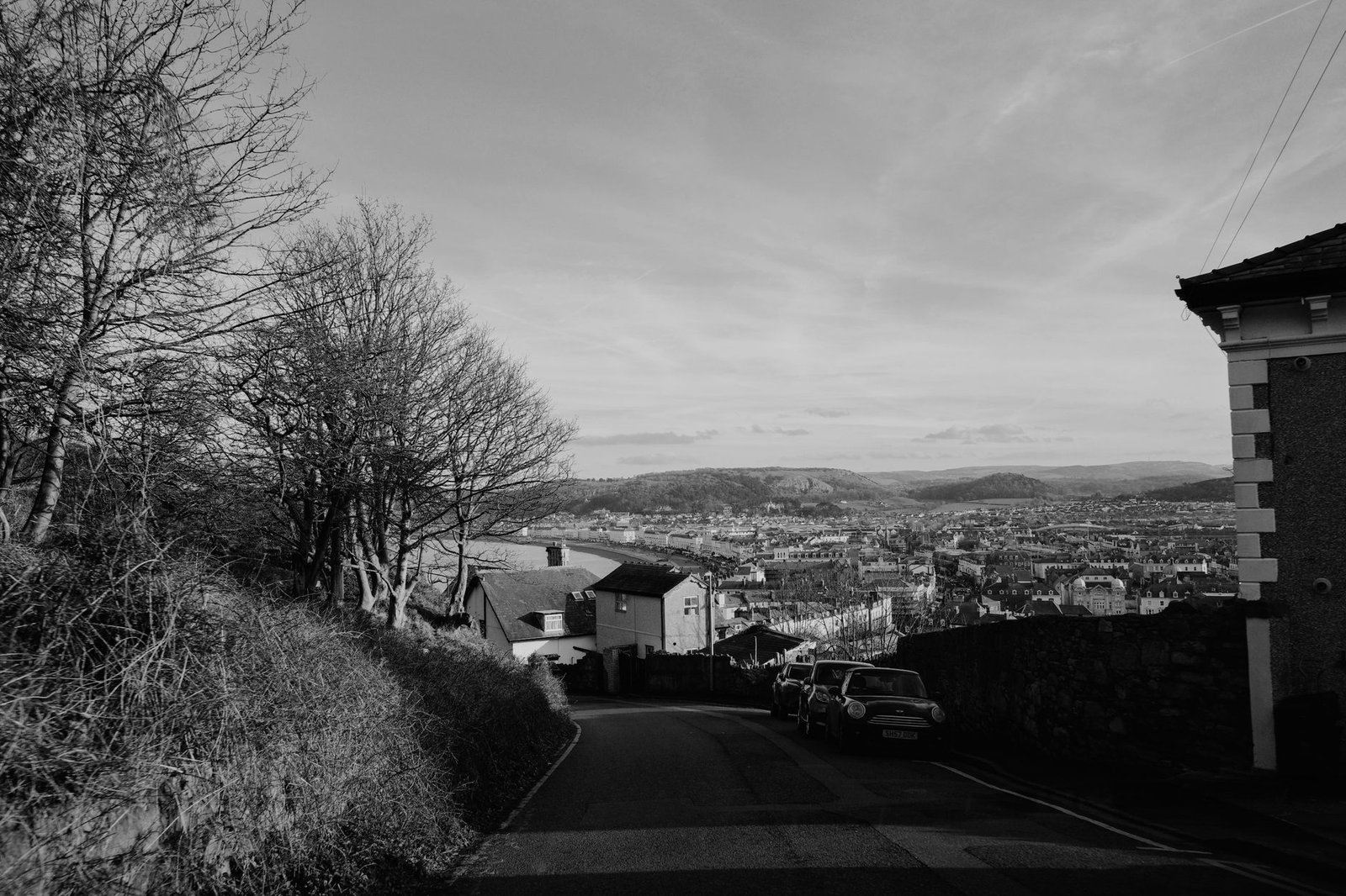 Black and white photo capturing the scenic landscape of North Wales with distant hills and a rural road.