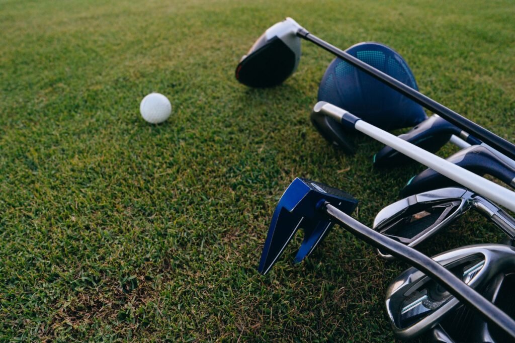 A close-up view of golf clubs and a golf ball on a lush green grass field.