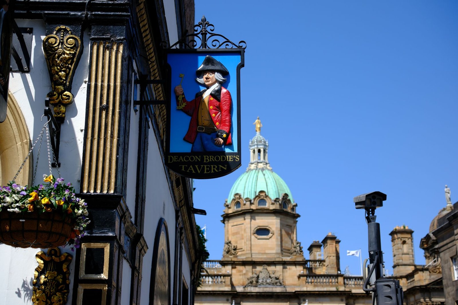 Deacon Brodie's Tavern sign with a historic building in Edinburgh, Scotland.