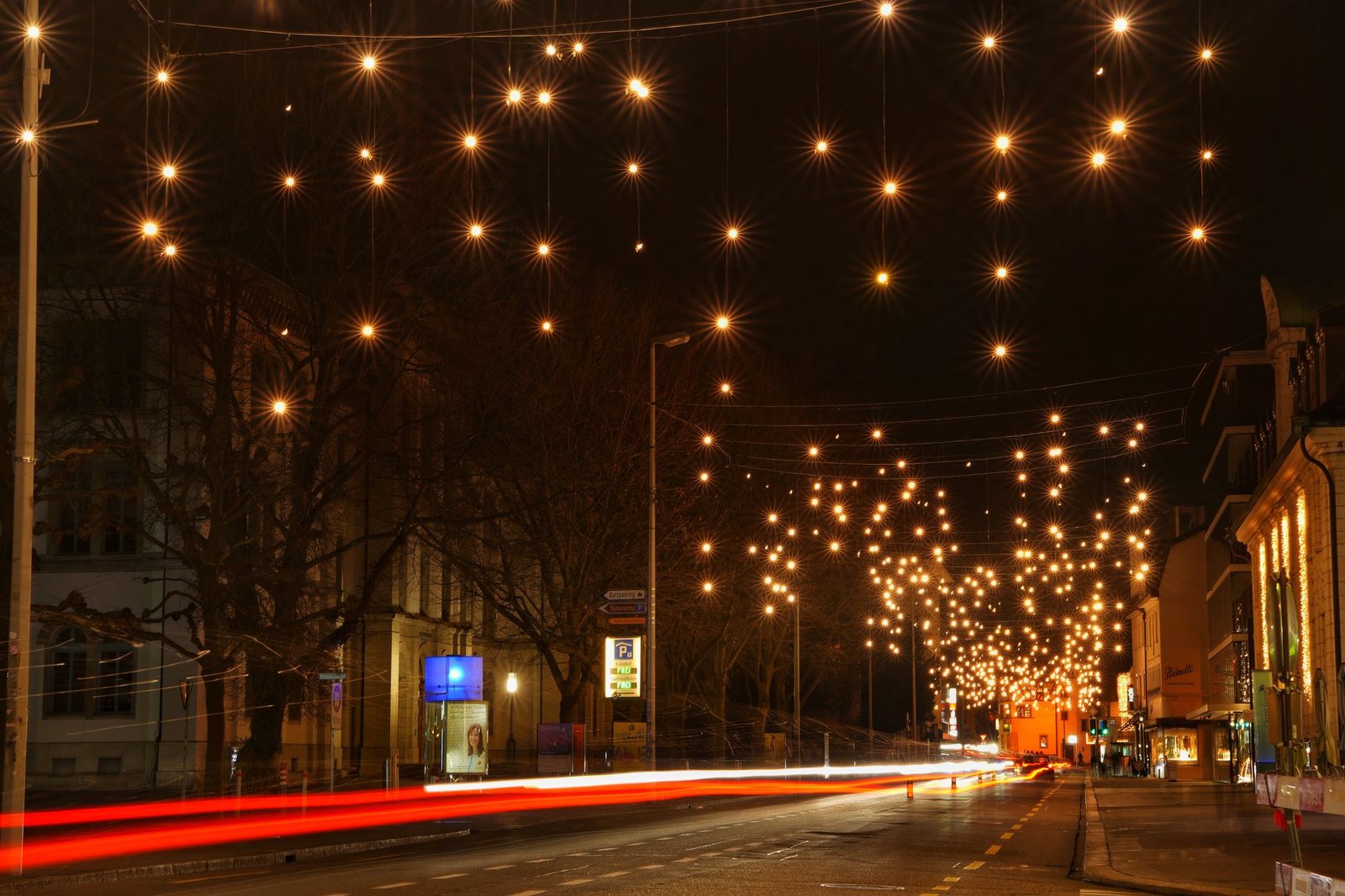Night city street with festive lights and long exposure car trails creating a magical atmosphere.