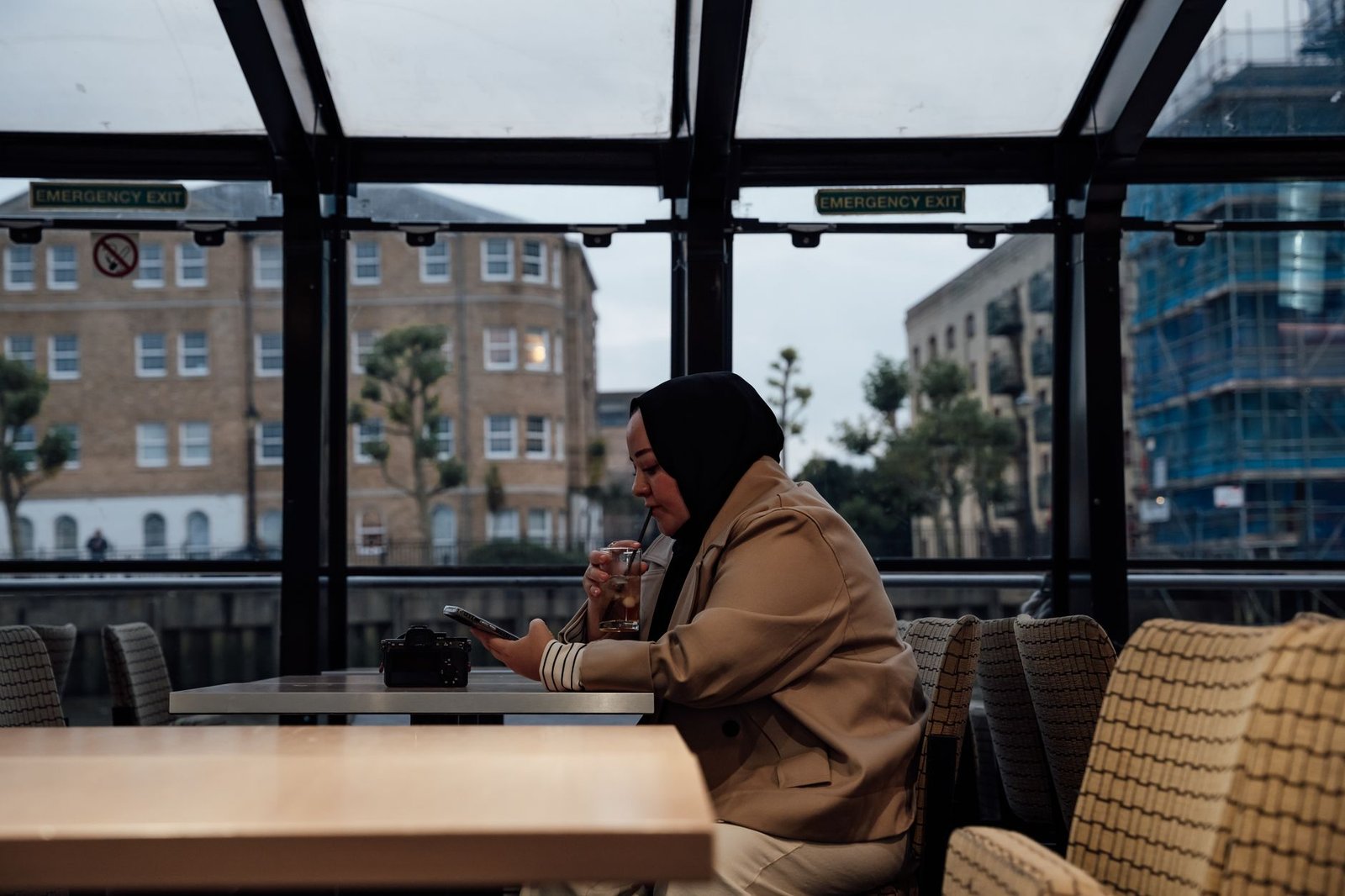 Visitor discreetly reviewing travel plans beside a London hotel window