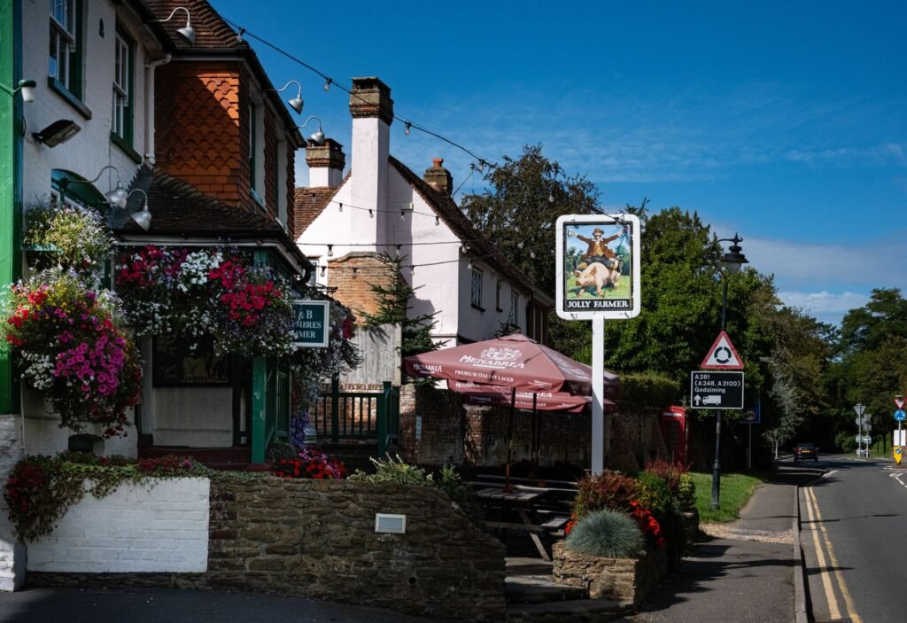 A picturesque view of the Jolly Farmer pub in Bramley, England, with vibrant flowers and clear skies.