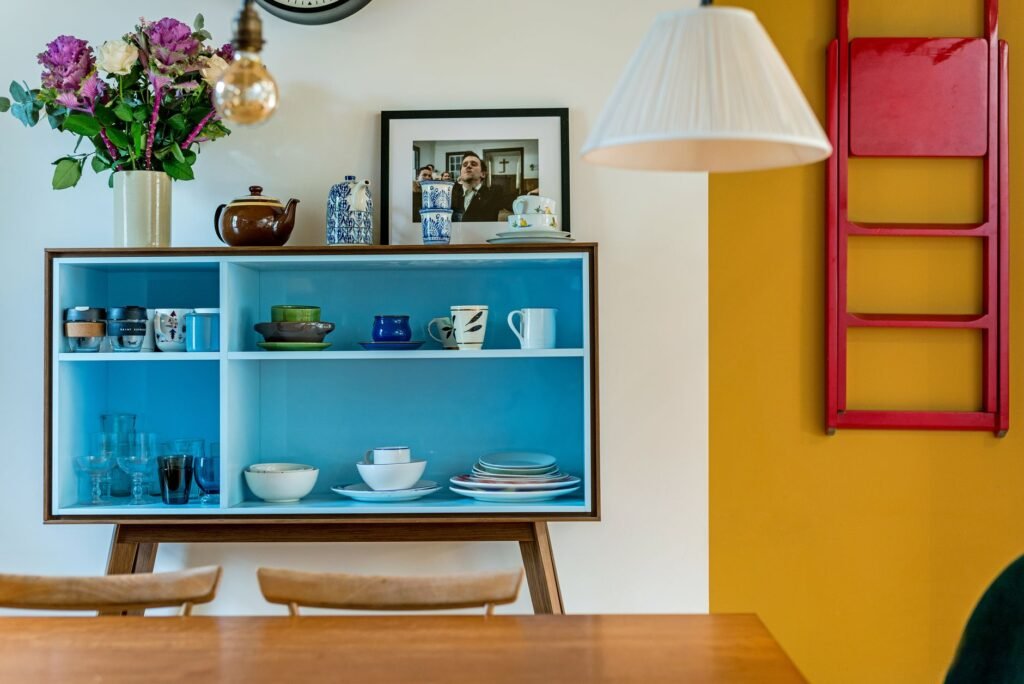 Stylish interior featuring blue shelves with dishes and decor against a colorful backdrop.