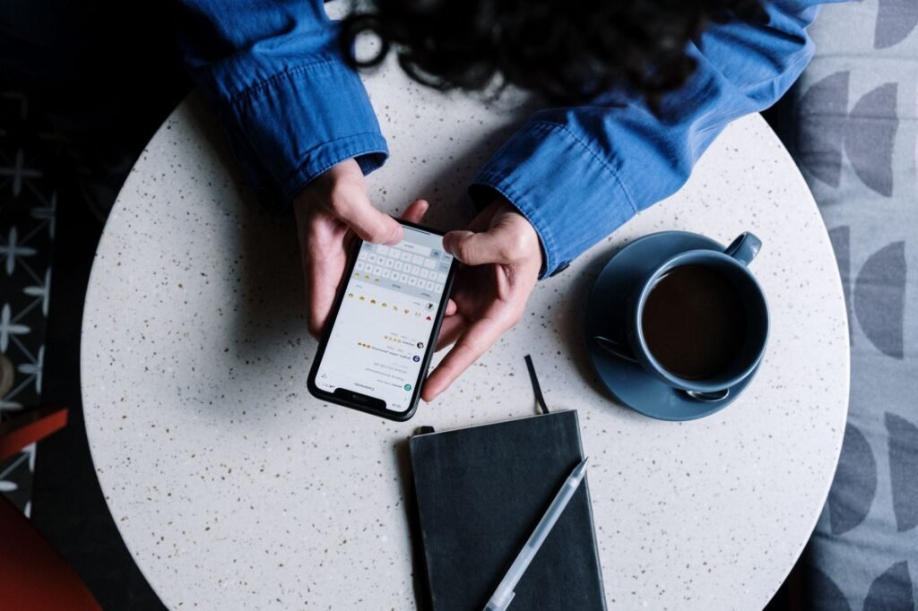 Hands preparing a clear message on a smartphone beside a notebook