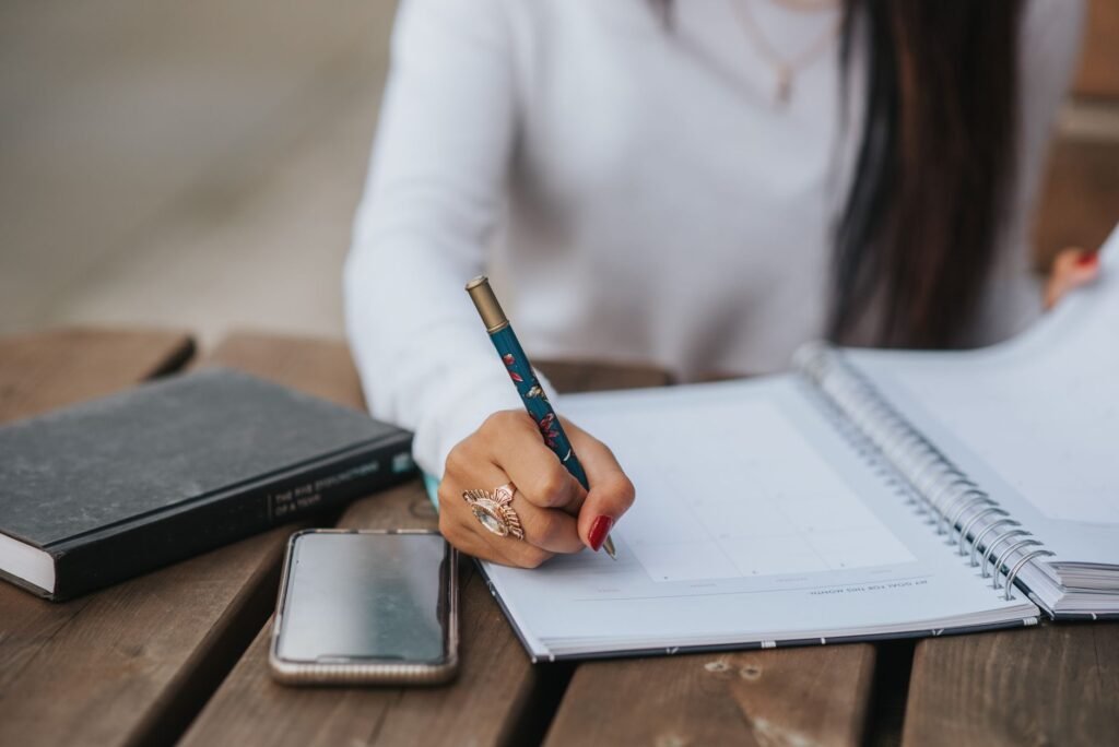 Writing down appointment details beside a smartphone
