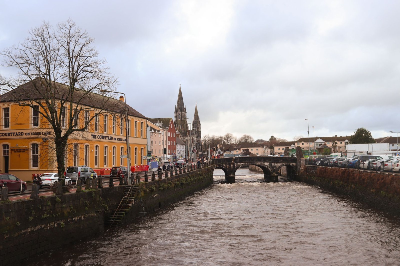 Charming city view featuring bridge over river, historic buildings, and overcast skies in winter.