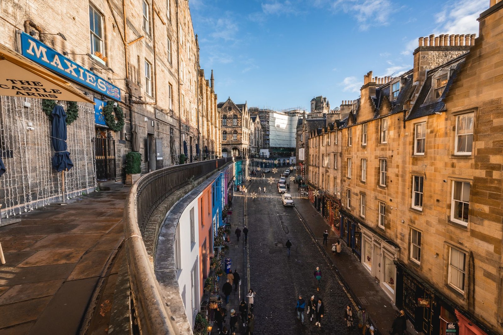 Vibrant view of historic Victoria Street in Edinburgh's Old Town, showcasing colorful shops and cobblestone path under a clea