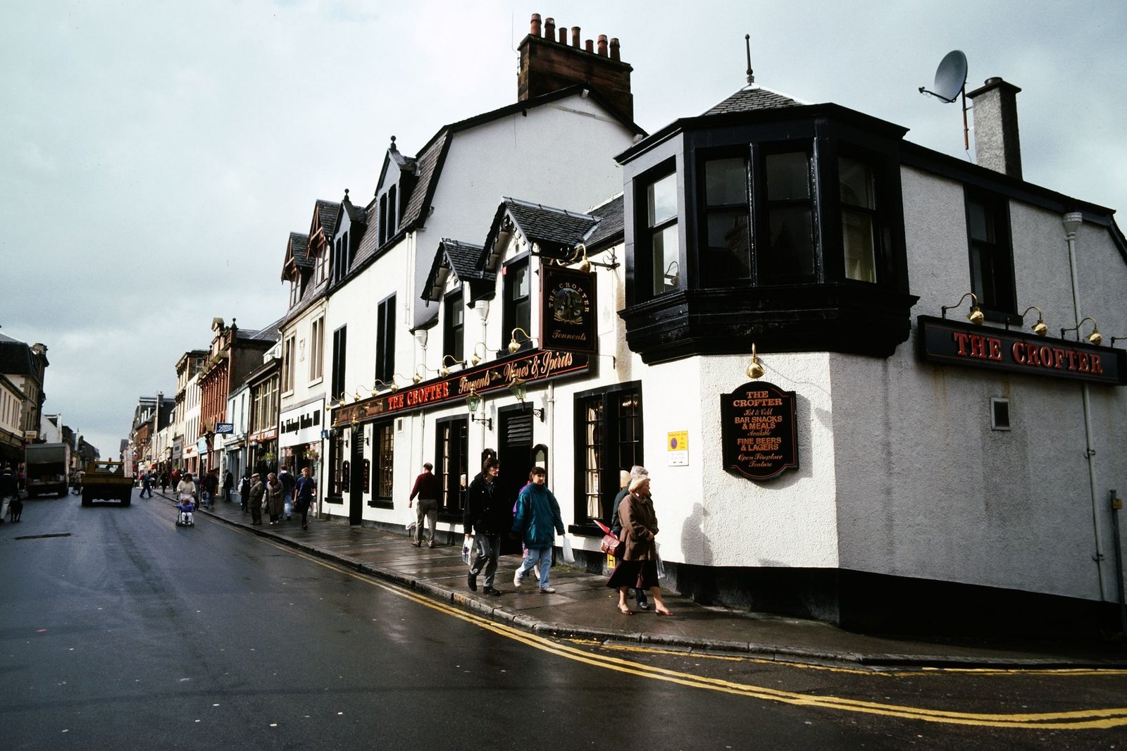 Busy street scene outside The Crofter in Scotland on a cloudy day.