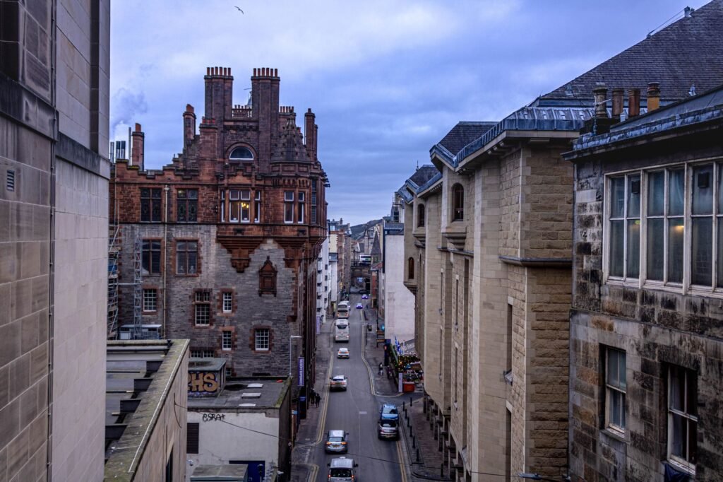 View of a narrow street in Edinburgh with historical buildings on an overcast day.