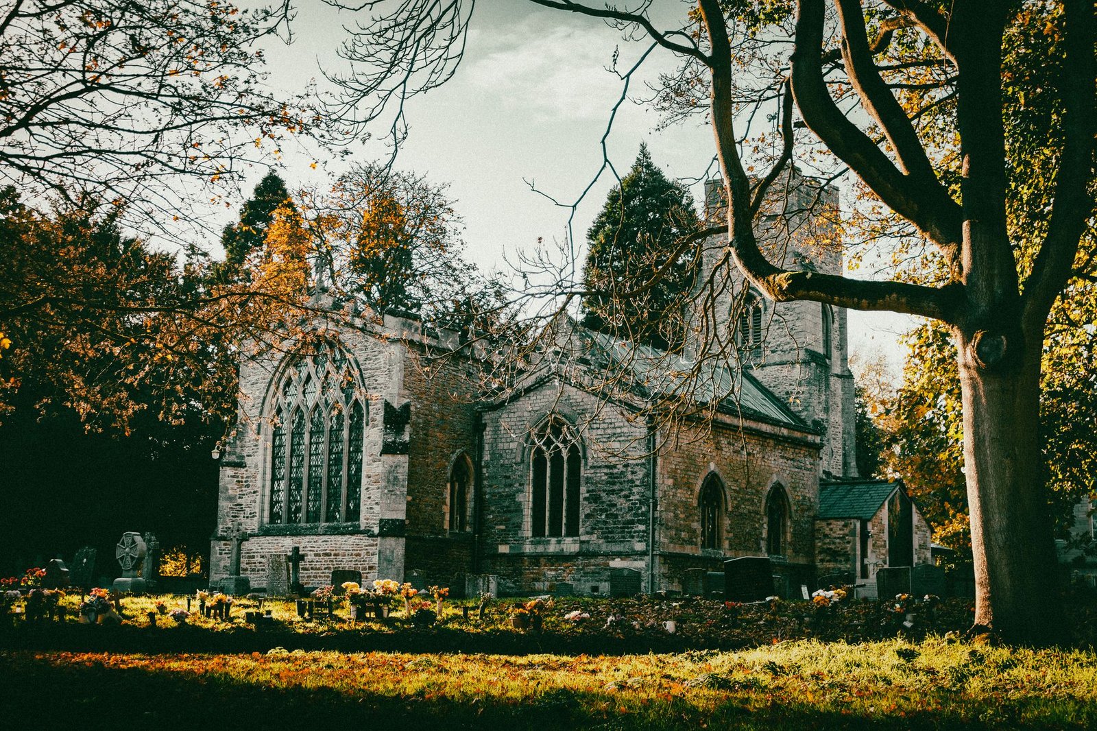 Beautiful autumn scene of a historic church surrounded by a peaceful cemetery in Peterborough, England.