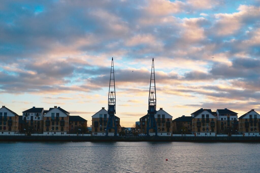 Scenic view of urban waterfront buildings and cranes at sunrise in Greater London, UK.