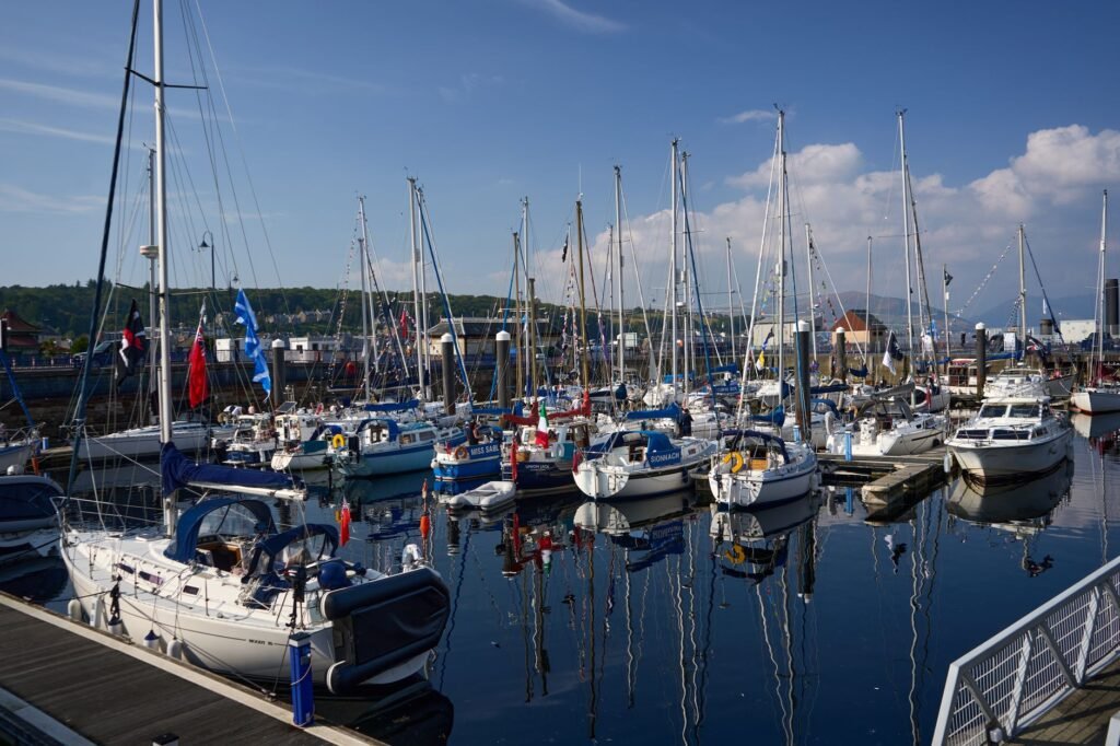 Vibrant sailboats at Rothesay Marina under a clear blue sky, showcasing a serene summer seascape.