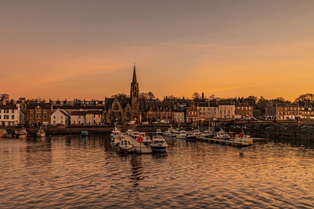 Serene sunset over Newhaven Harbor with docked boats and historic townscape.