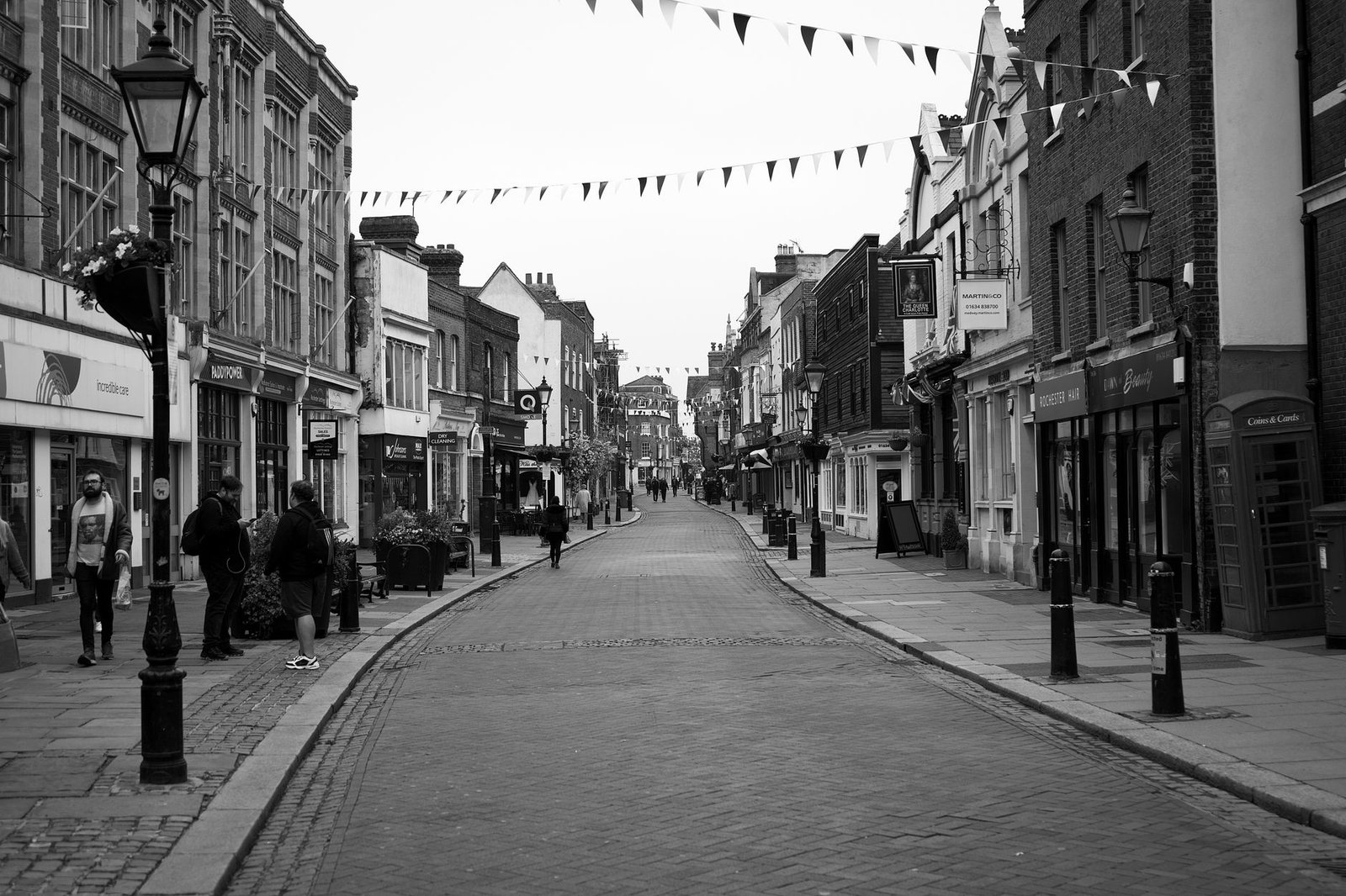 Historic street scene in Rochester, UK, showcasing old architecture and vibrant street life in monochrome.