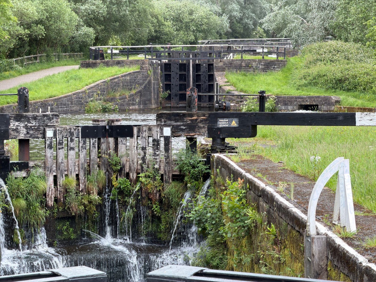 Charming canal lock with lush greenery in Wigan, England, showcasing engineering history.