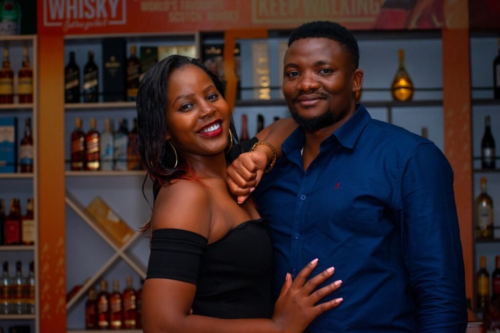 Charming couple smiling and embracing inside a whiskey bar, showcasing love and happiness.