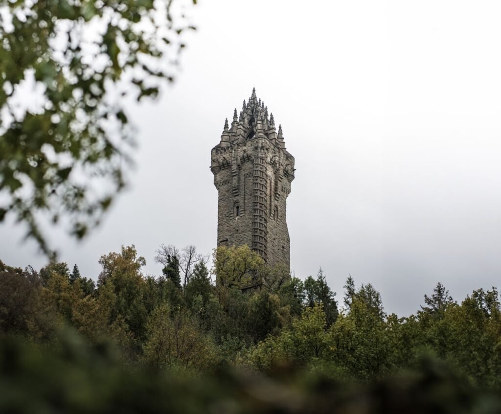 The iconic Wallace Monument tower in Stirling, Scotland stands tall against a cloudy sky.