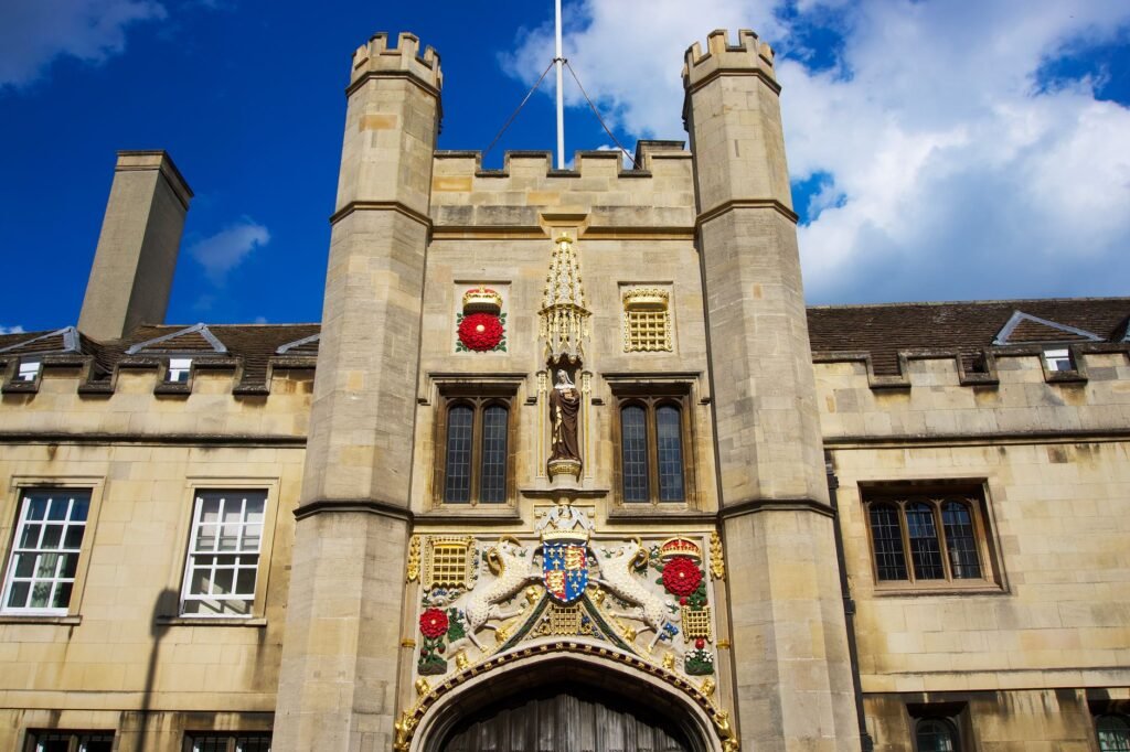 Detailed view of the historic entrance at Christ's College Cambridge under a bright blue sky.