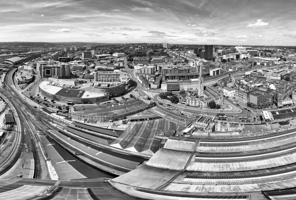 Black and white aerial view of a cityscape featuring railway tracks and modern architecture.