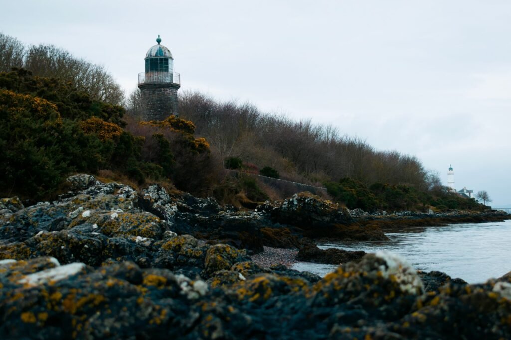 Scenic coastal landscape featuring a historic lighthouse along the rocky shores of Scotland.