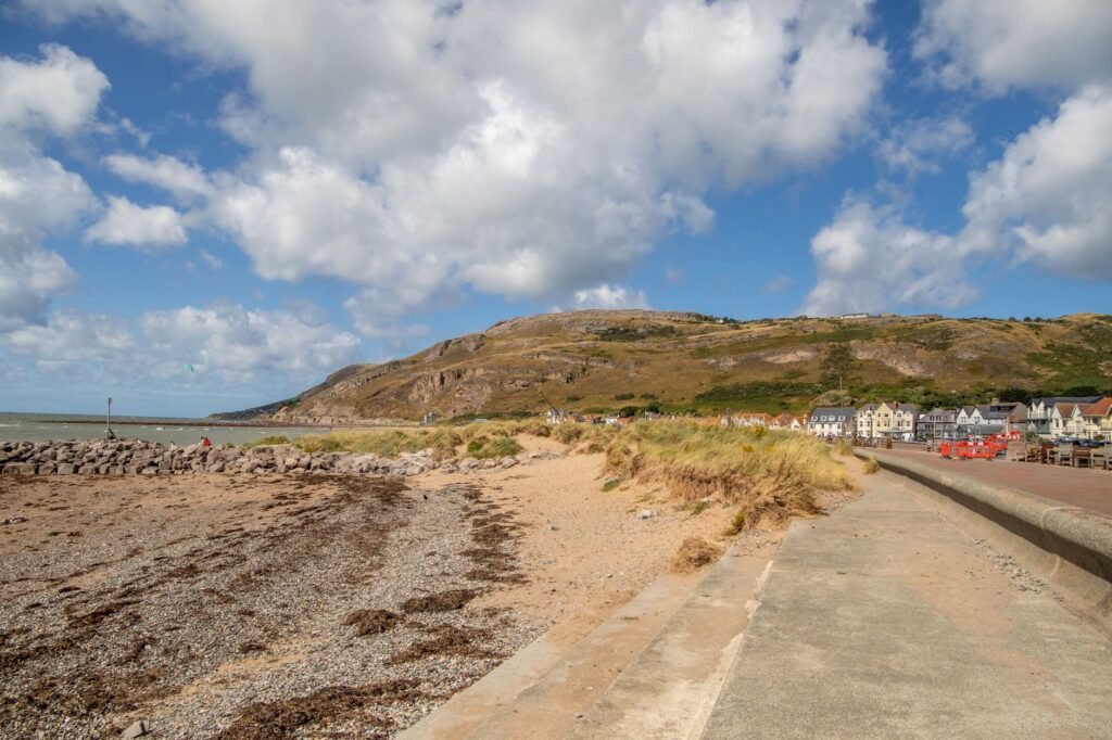 Scenic view of a beach in Wales with pebbles, seaweed, and clear skies. Perfect for travel and vacation themes.