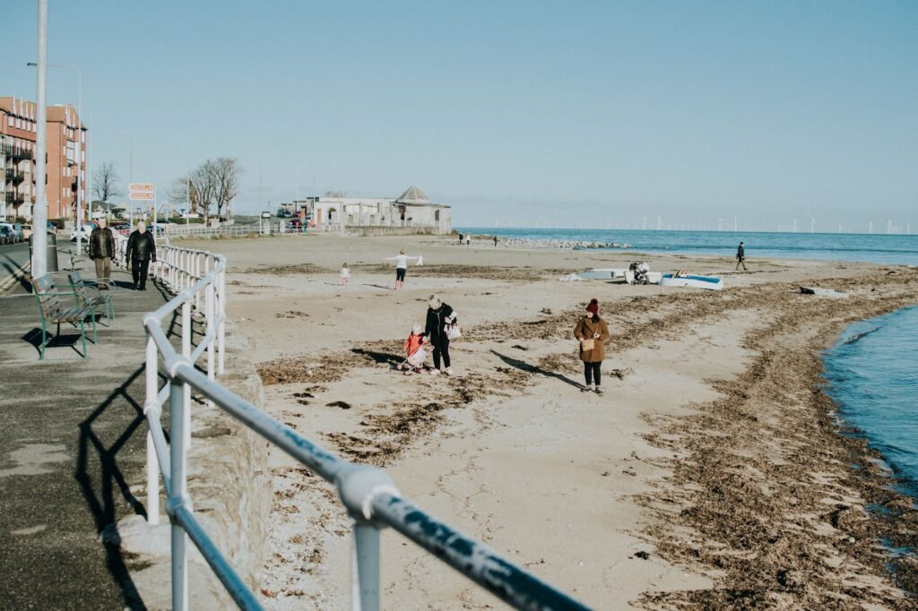 People enjoying a sunny day at a quiet beachside promenade.