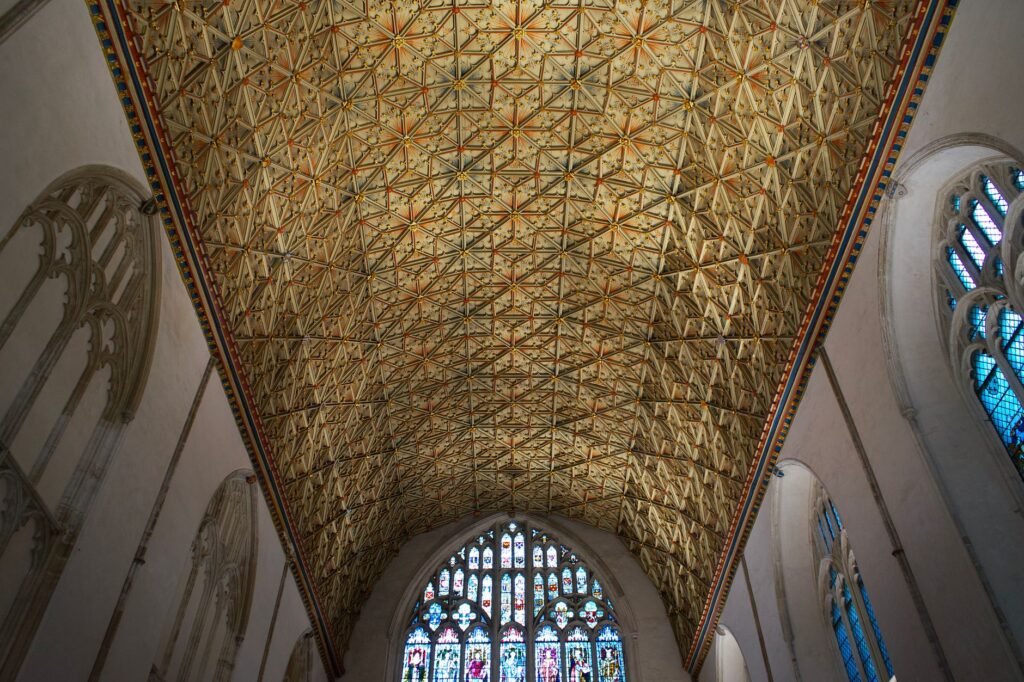 Detailed view of the ornate ceiling and stained glass windows in Canterbury Cathedral, England.