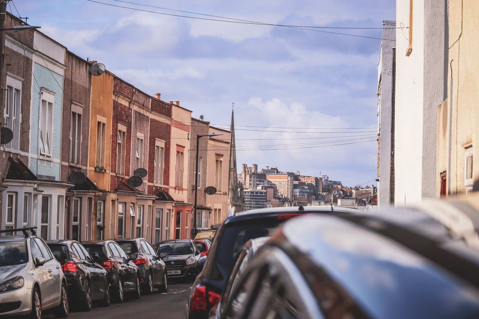 Charming street view in Bristol, England, showcasing colorful townhouses and parked cars.