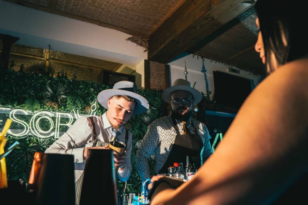 Bartenders crafting cocktails in a lively bar with neon lights and a vibrant atmosphere.