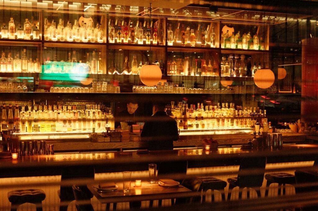Warm and inviting bar interior in New York, featuring illuminated shelves of bottles and soft ambient lighting.