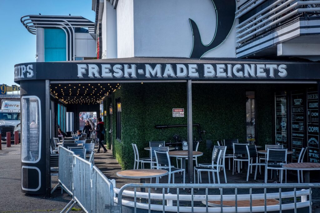 Quaint urban cafe offering fresh beignets with outdoor seating and vibrant decor.