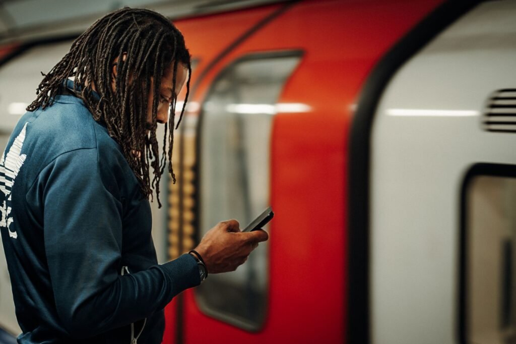 Adult checking a smartphone near a London transport entrance