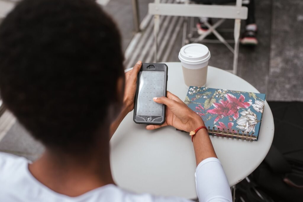 Traveller reviewing information on a smartphone beside a notebook